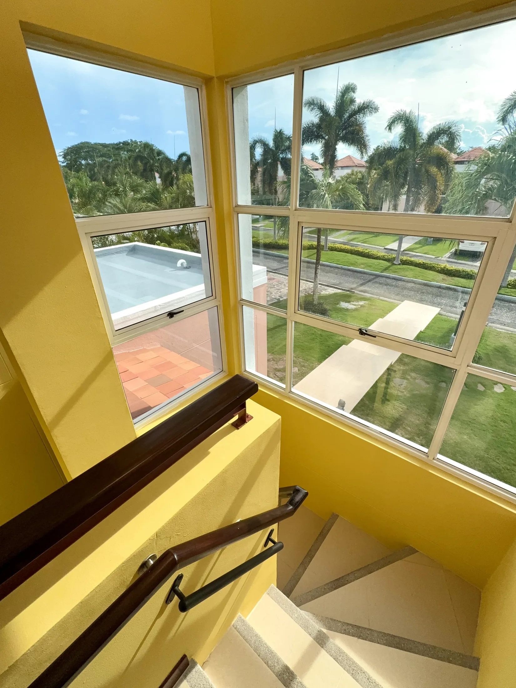 Stairwell corner window with palm tree views and wood-beam ceiling
