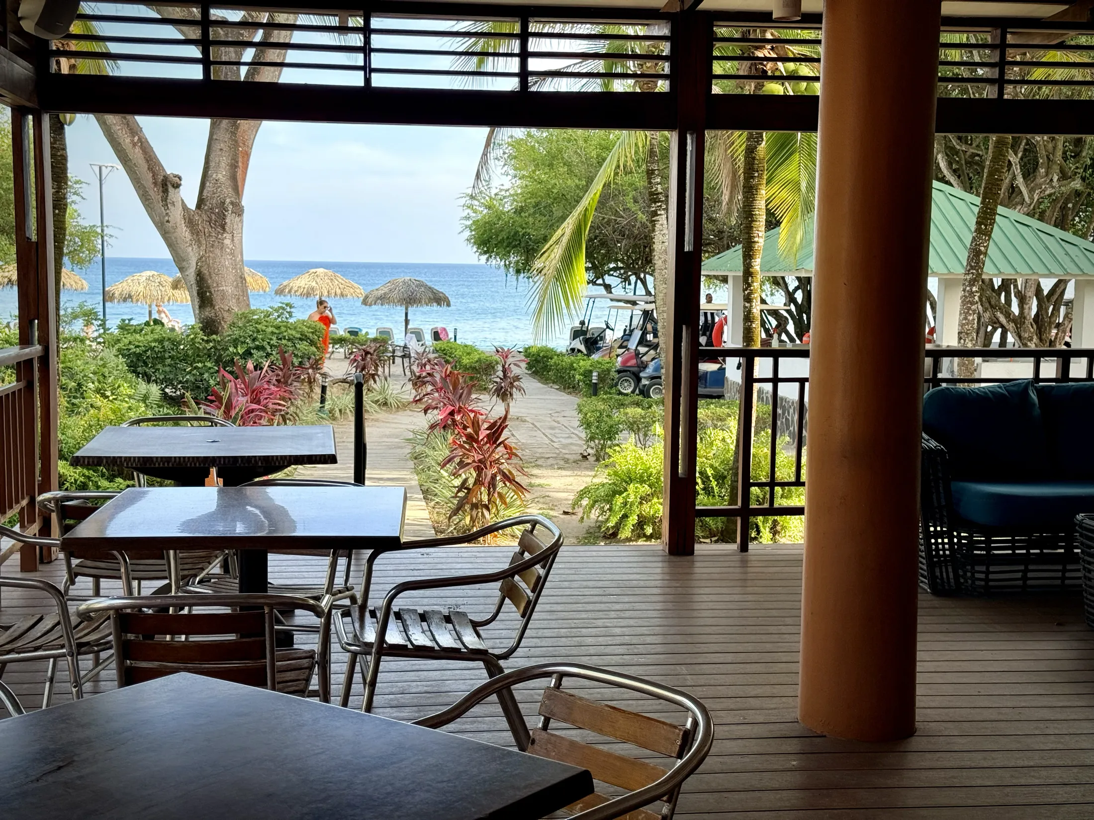 Beach club seating area with ocean view, thatched umbrellas, and tropical landscaping