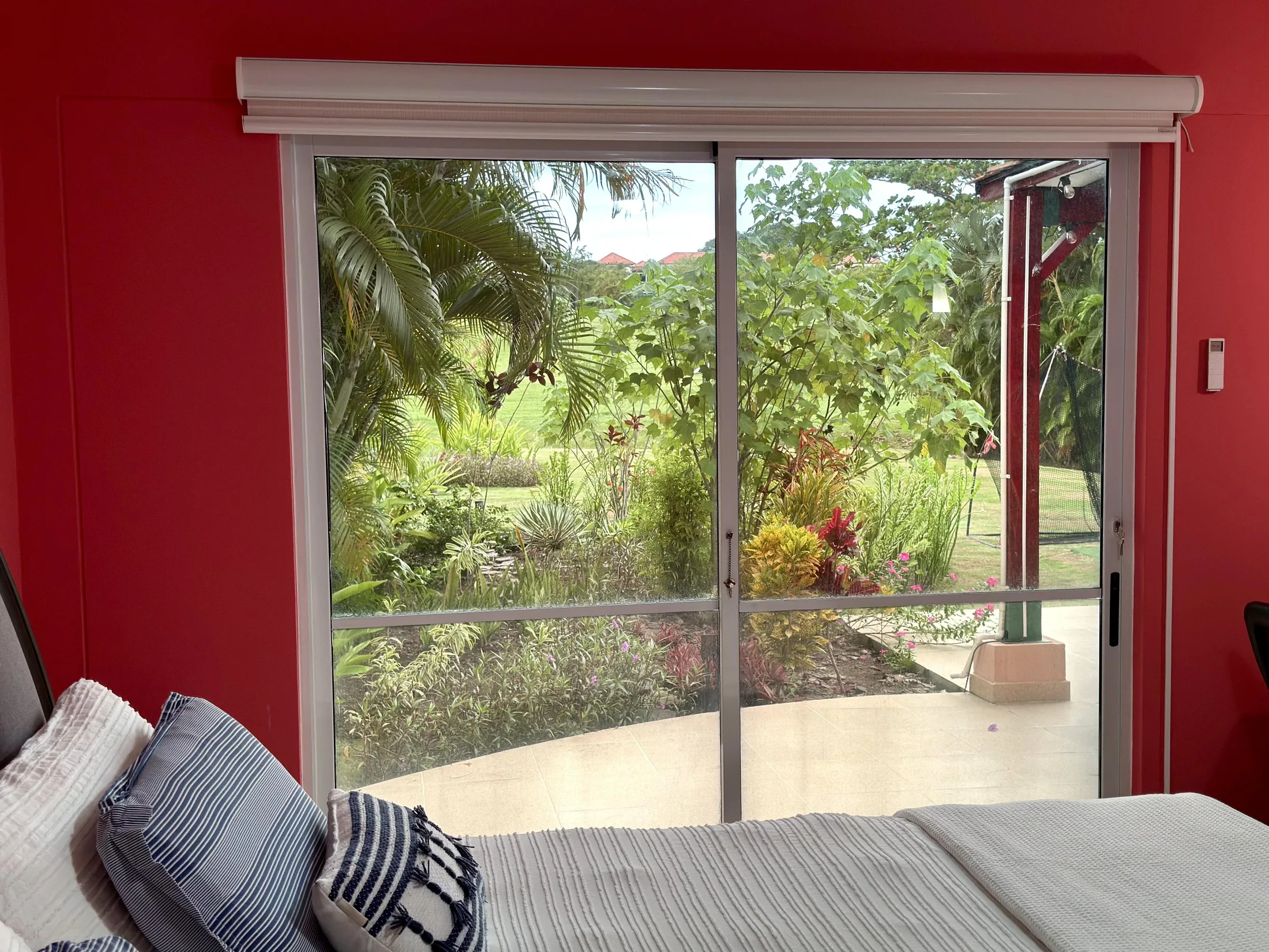 Coral bedroom sliding door view to lush tropical garden and patio