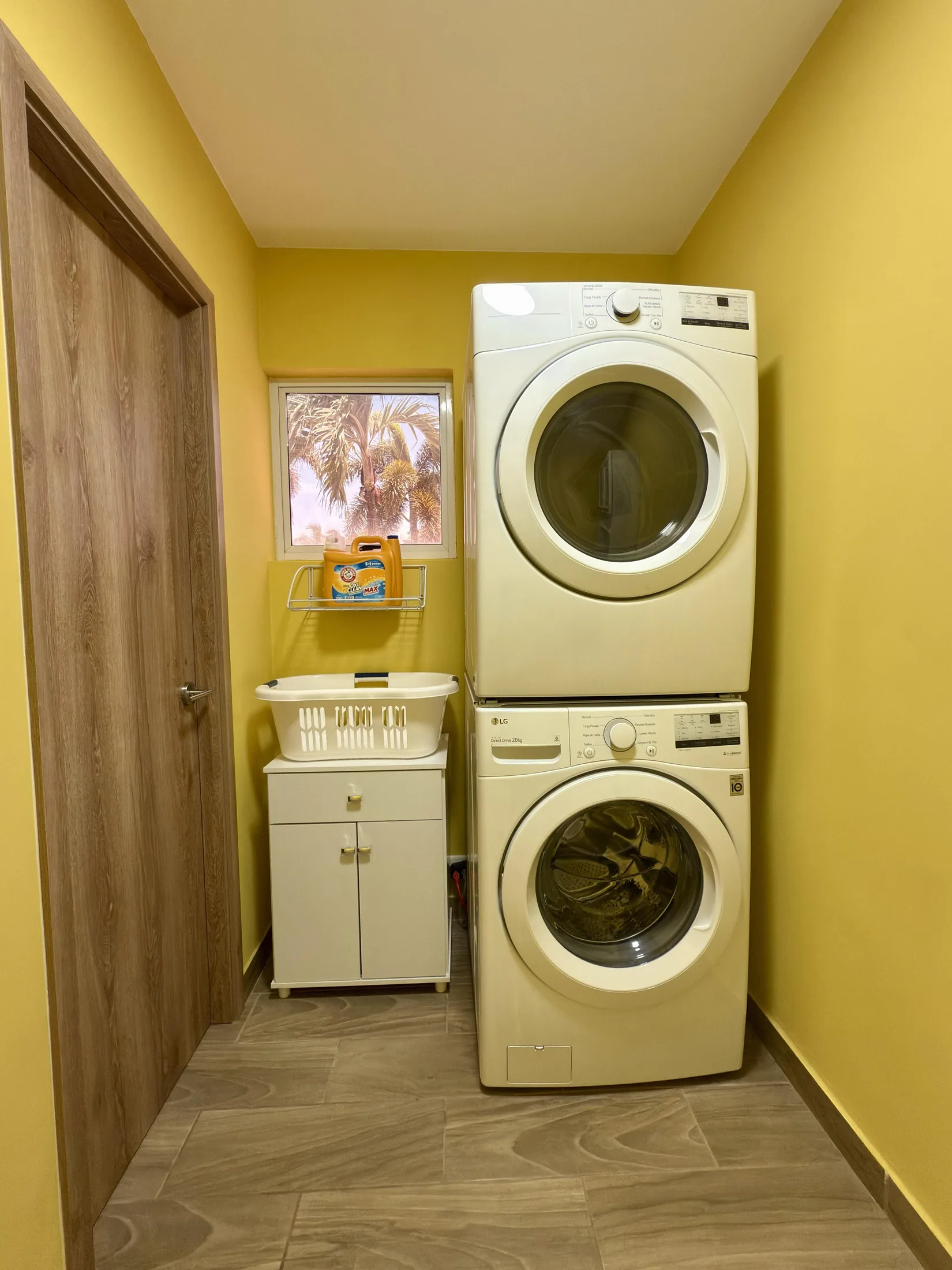 Laundry room alternate angle with stacked machines, basket, and doorway