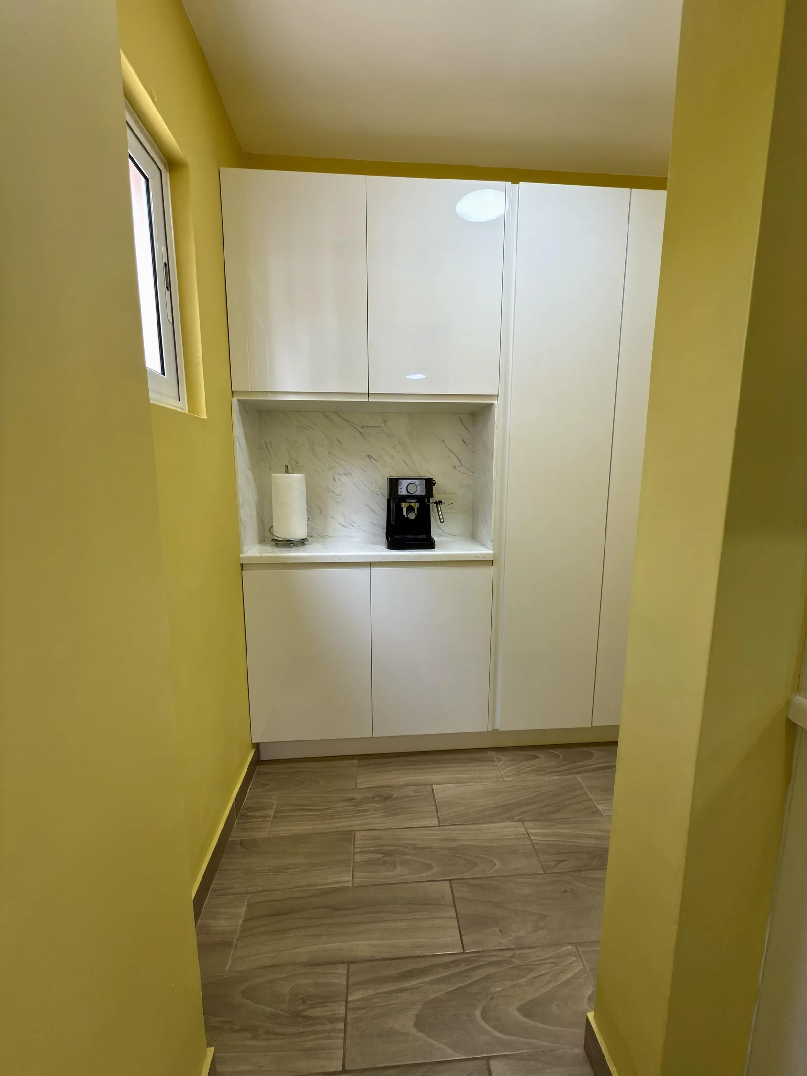 Pantry niche with coffee machine, white cabinets, and marble backsplash