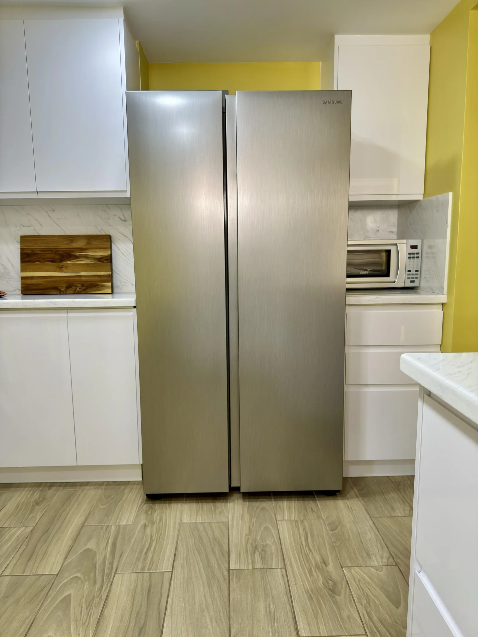 Samsung stainless steel side-by-side refrigerator with white cabinets and microwave nook