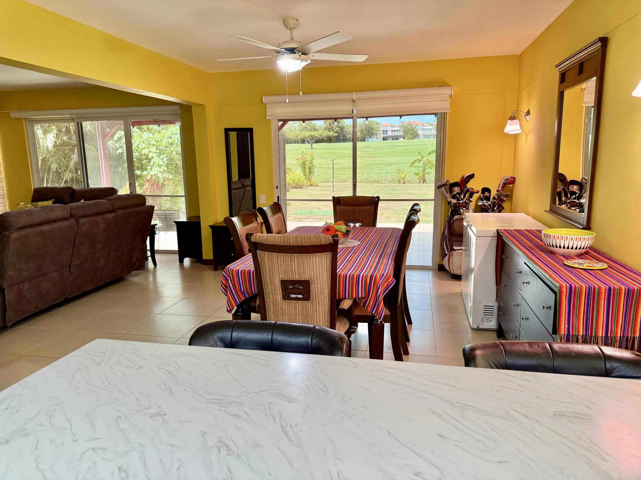 Pink bedroom with vaulted wood-beam ceiling, white distressed furniture, pink pillows, and colorful striped bench