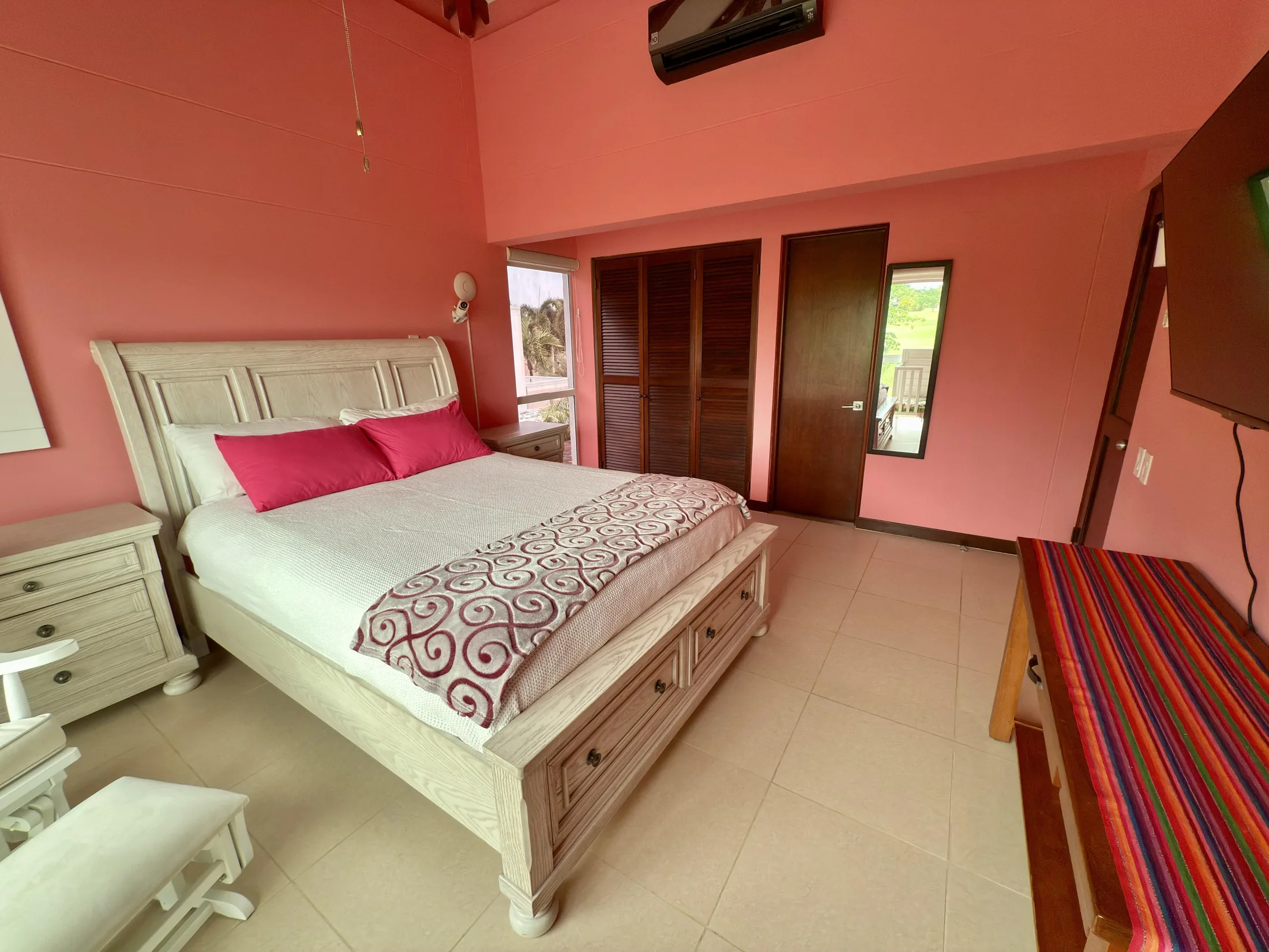 Pink bedroom closet side alternate angle with striped bench and dark wood doors