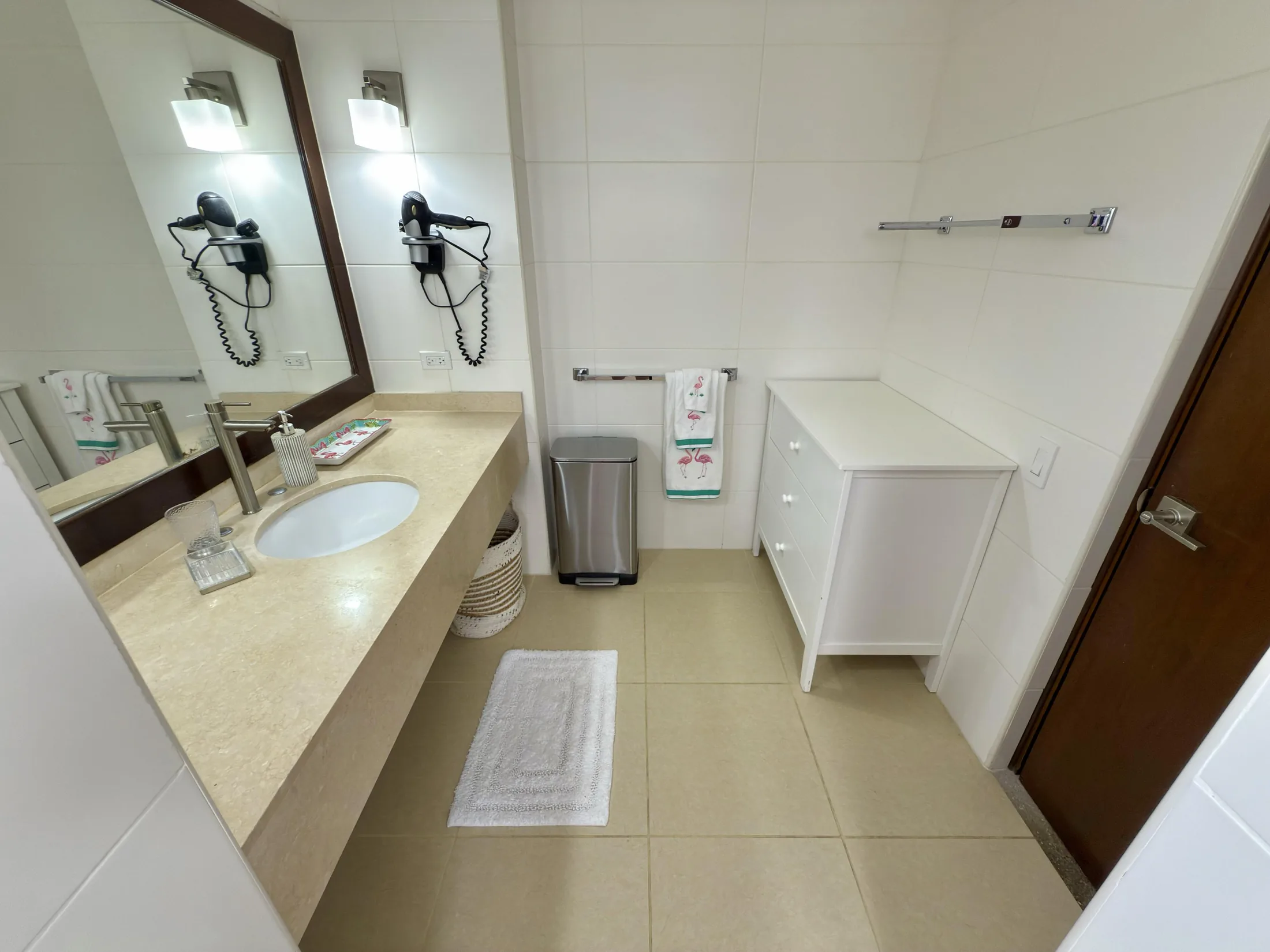 Bathroom vanity with stone countertop, wood-framed mirror, hair dryer, and storage cabinet